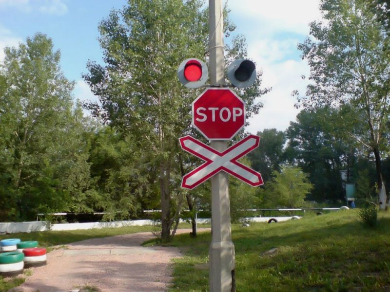 Знак стоп на белом фоне перед железнодорожным переездом